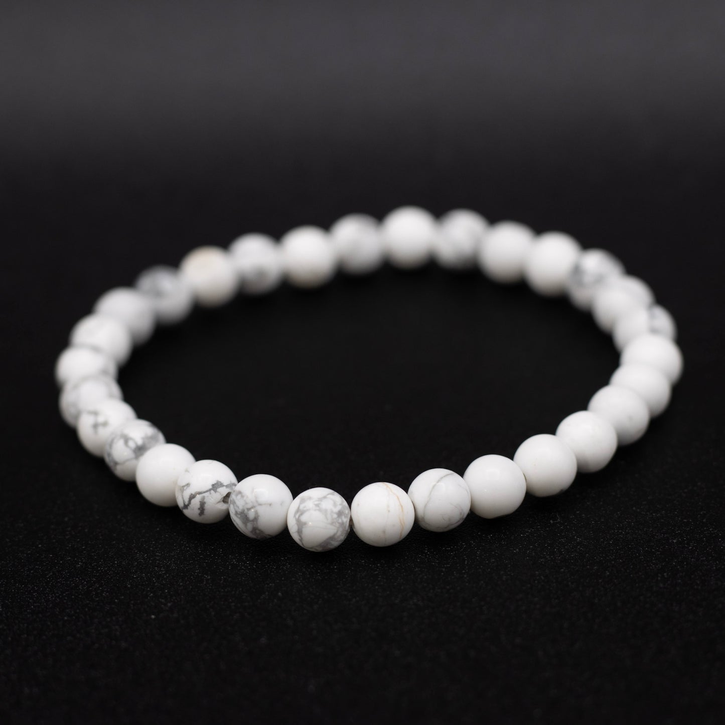 White beaded bracelet on a black background